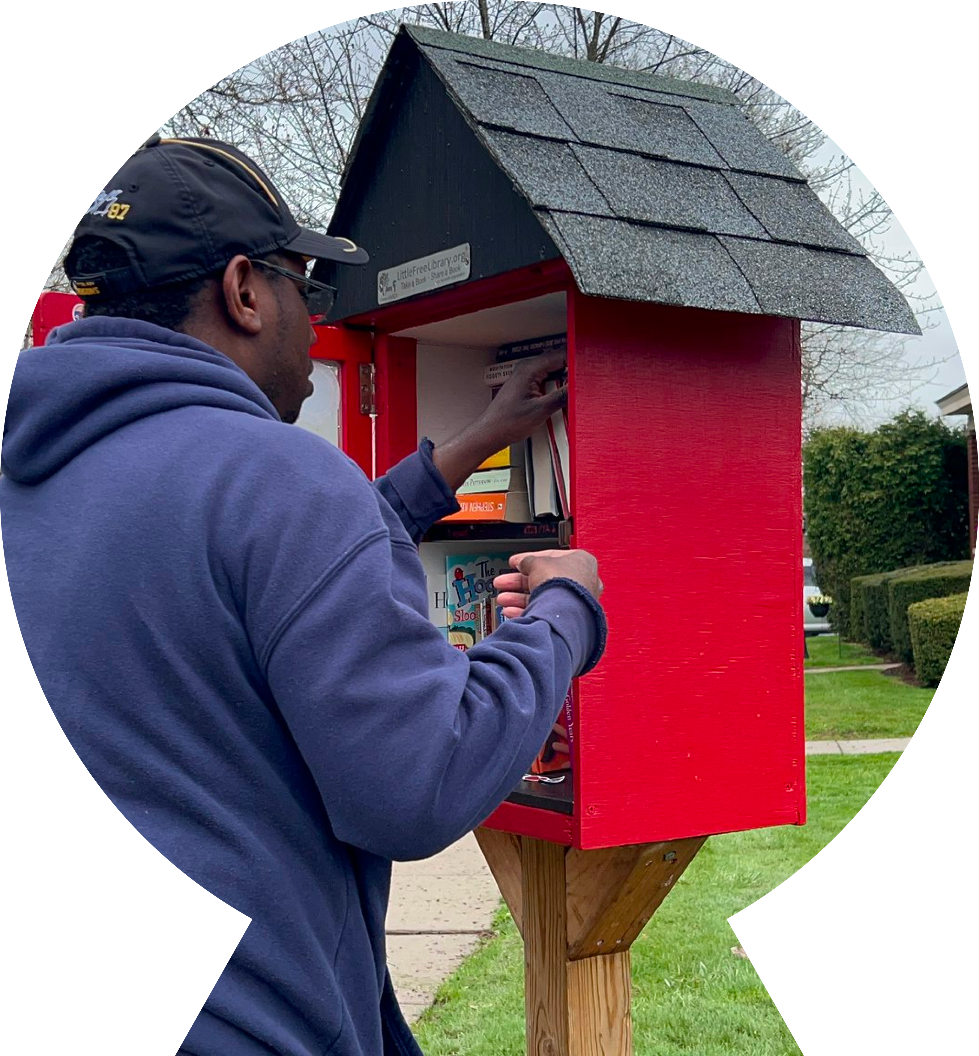 Young man searching inside the "Little Free Library" found in a park. Young man searching inside the "Little Free Library" found in a park.