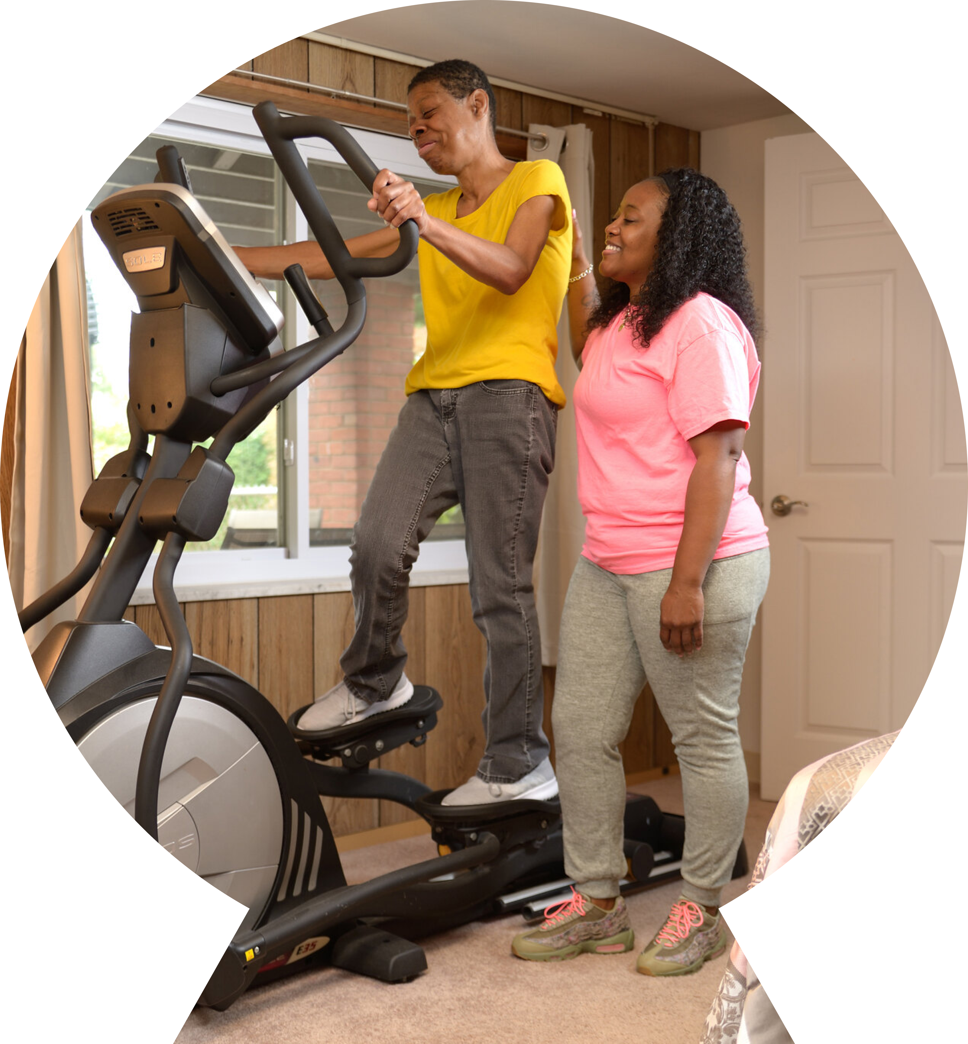A woman working out on an elliptical with assistance. A woman working out on an elliptical with assistance.