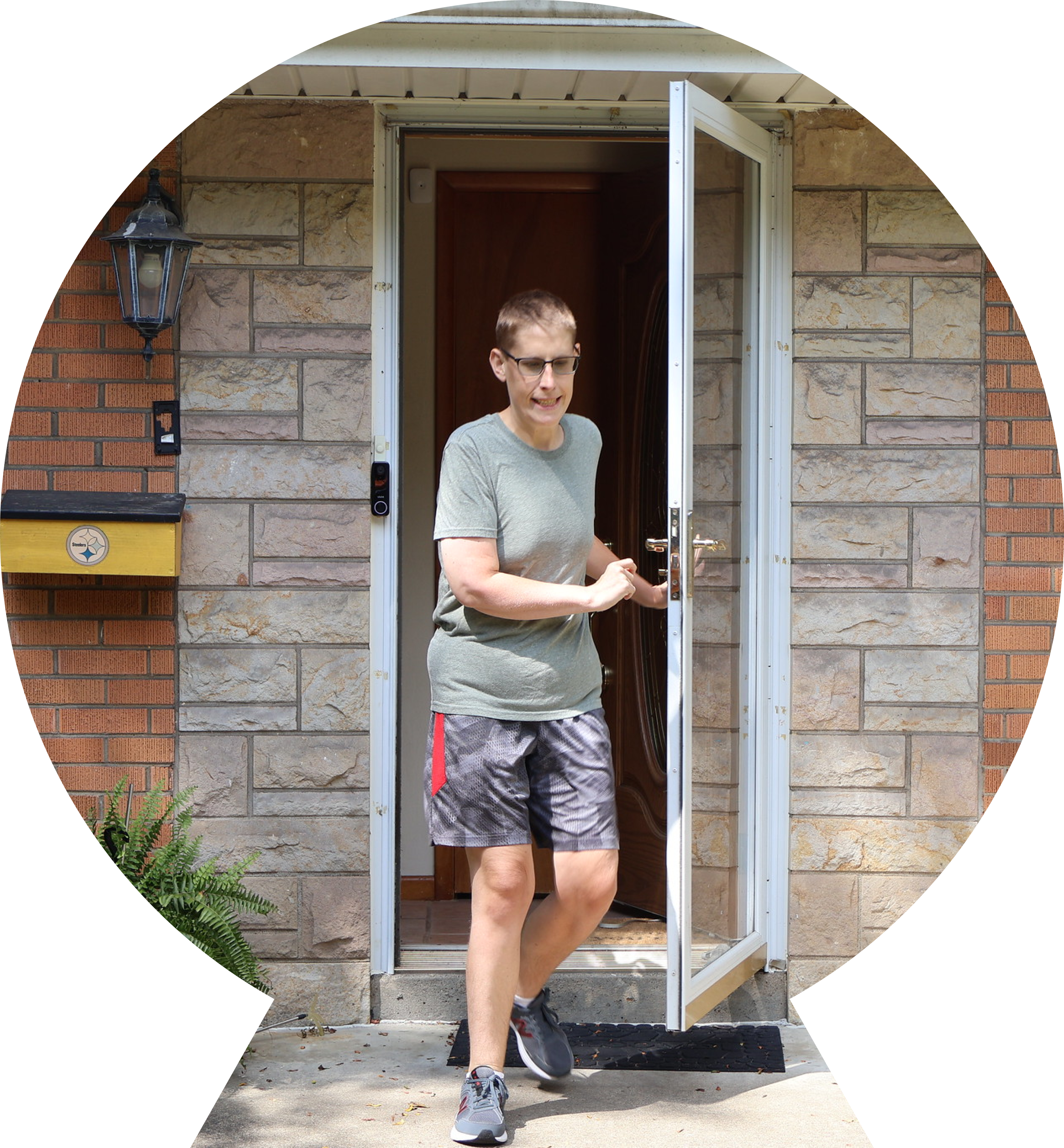 Young man with glasses walking out of the door quickly.